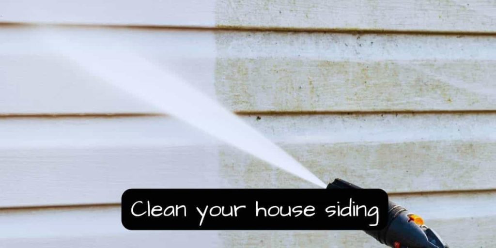 cleaning the house exterior siding using a garden hose with jet nozzle