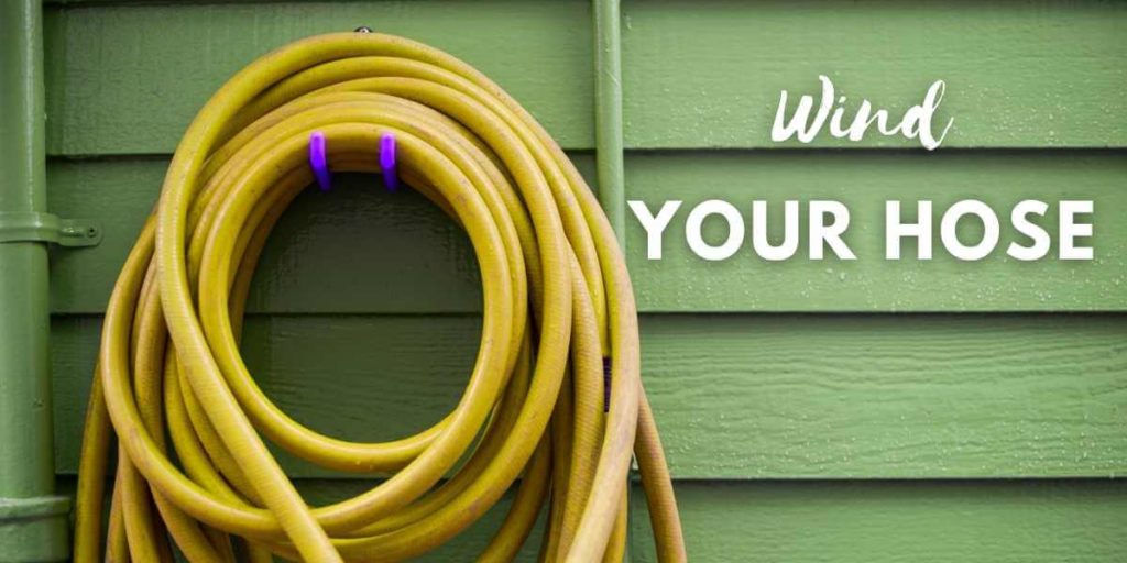 coiled garden hose on wall-mounted hose holder