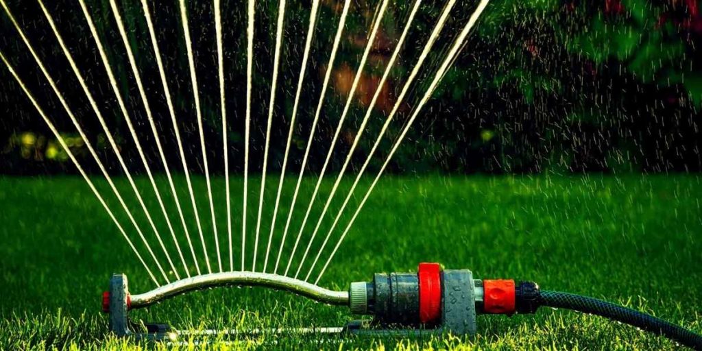 Portable lawn sprinkler connected to a garden hose